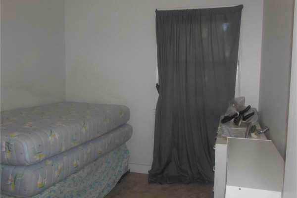 Bedroom with two mattresses stacked on a box spring and a grey curtain. - 1742 Quebec Street, Regina