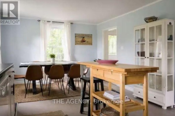 Dining room with a long table, chairs, a cabinet, and light blue walls. - 12 - 1743 County Road, Prince Edward County