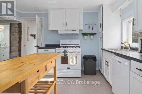 Kitchen with white cabinets, a white gas stove, black countertops, and a wooden island. - 12 - 1743 County Road, Prince Edward County