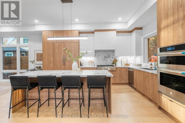 Modern kitchen with island, marble counters, wood cabinets, and stainless steel appliances - 175 Harewood Avenue Toronto