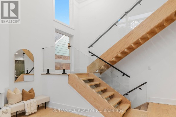 Modern wooden staircase with glass railing and arched mirror - 175 Harewood Avenue Toronto