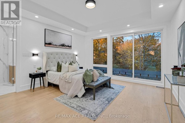 Bedroom with tufted headboard, large windows overlooking trees, and hardwood floors - 175 Harewood Avenue Toronto
