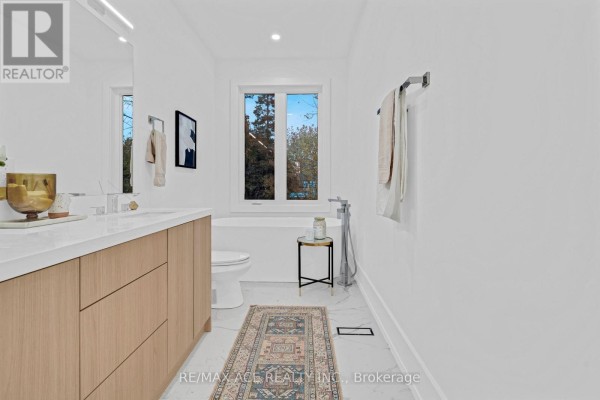 Modern bathroom with soaking tub, vanity, and window - 175 Harewood Avenue Toronto