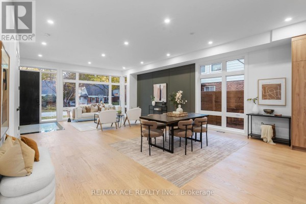 Living and dining area with dark wood table, white chairs, and modern furniture. - 175 Harewood Avenue, Toronto