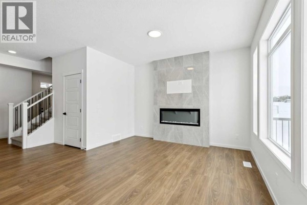 Living room featuring a modern fireplace and large windows for natural light. - 175 Herron Landing Ne, Calgary