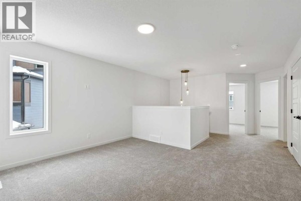 Cozy loft area with carpet flooring and a pendant light fixture. - 175 Herron Landing Ne, Calgary
