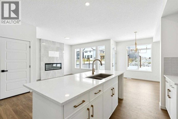 View of kitchen and living area with large windows and a fireplace. - 175 Herron Landing Ne, Calgary