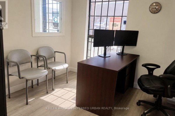 Waiting area with two grey chairs, a desk with two monitors, and a locked filing cabinet. - 175 Limestone Crescent, Toronto