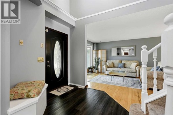 Entranceway showing a black front door with oval glass and a grey bench. - 175 Shannon Circle Sw, Calgary