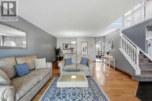 Living room with light beige sofas, a blue patterned rug, and hardwood floors. - 175 Shannon Circle Sw, Calgary