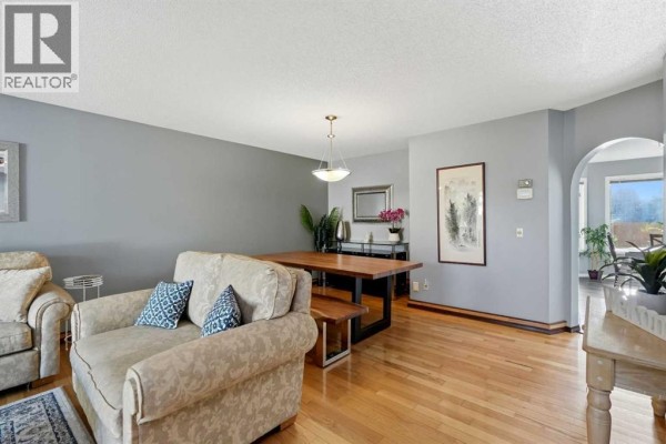 Dining area with a wooden table and bench seating, adjacent to the living room. - 175 Shannon Circle Sw, Calgary
