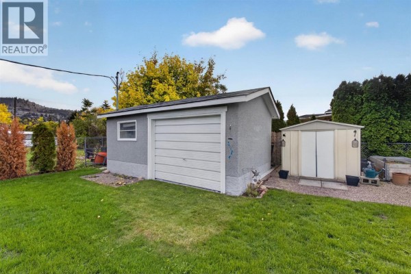 Detached garage with a white sectional door and a storage shed next to it. - 175 Venus Road, Kelowna
