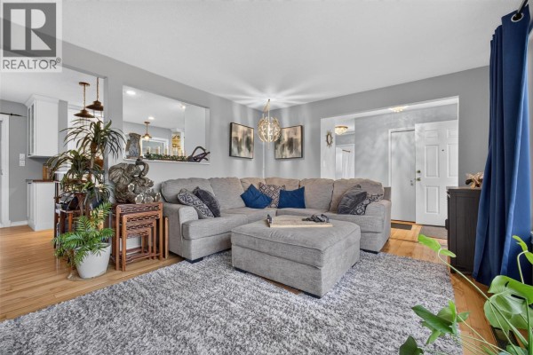 Living room featuring a large sectional sofa, ottoman, shag rug, and hardwood floors. - 175 Venus Road, Kelowna