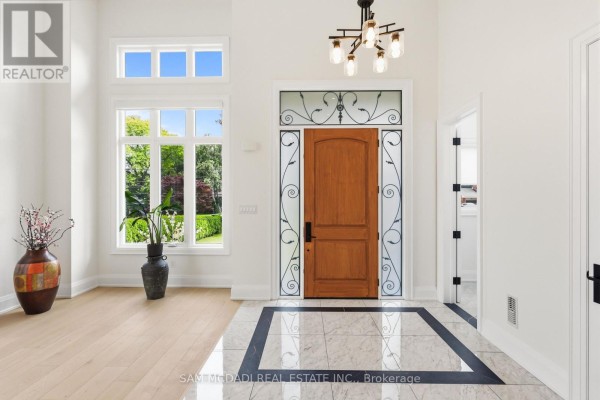 Spacious foyer with a wooden front door, marble tile floor, and large window. - 1750 Lincolnshire Boulevard, Mississauga