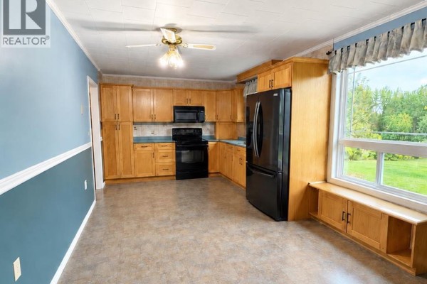 Kitchen with oak cabinets, black appliances, and a large window with built-in seating. - 17530 Township Road 763a, Rural Big Lakes County