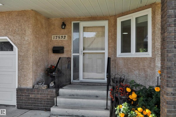 Entryway with light teal walls, wooden railing, and a coat rack. - 17532 Callingwood Rd Nw, Edmonton