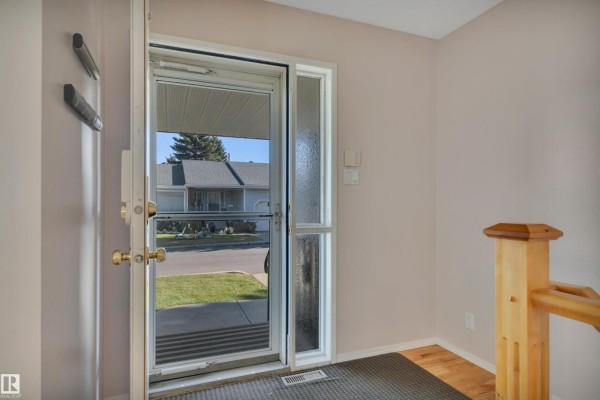 Open living area with light teal walls, hardwood flooring, and dining space visible. - 17532 Callingwood Rd Nw, Edmonton