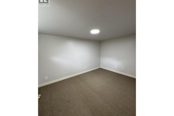 Unfurnished room with carpeted floor, light gray walls, and a circular ceiling light. - 1758b Western Parkway, Vancouver