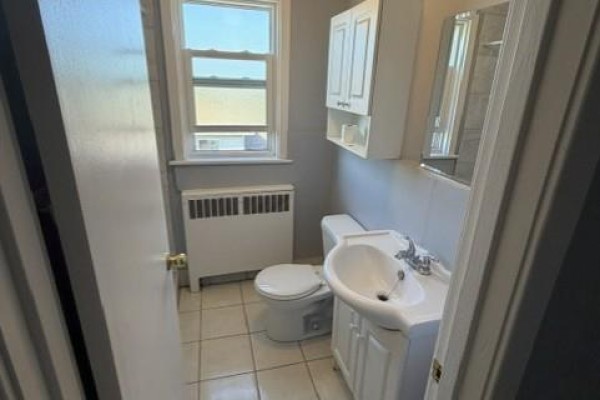 Bathroom with white toilet, sink, and vanity under a window. - 1759 King Street E Unit# 32, Hamilton