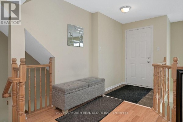 Interior entryway with white door, tiled floor, wooden banister, mirror, and storage bench. - 176 - 70 Edenvale Drive, Ottawa