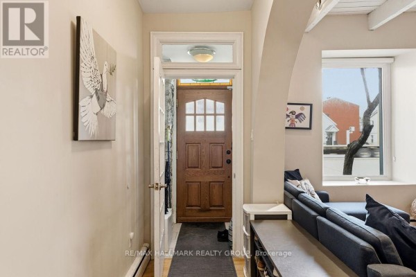Interior hallway view with a wooden front door and artwork on the wall. - 176 King Edward Avenue, Ottawa