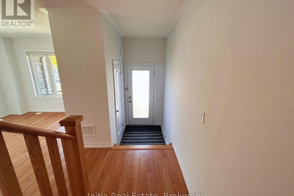Interior view of a townhouse entrance with a glass door, wood floor, and staircase. - 176 Lageer Drive, Whitchurch Stouffville