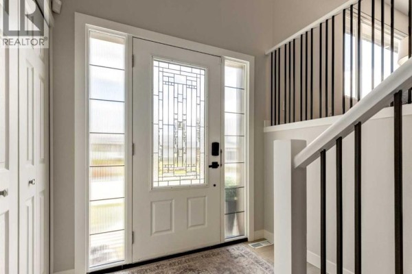 Front entrance with a white door, sidelight windows, and a staircase railing. - 176 Mapleburn Drive Se, Calgary