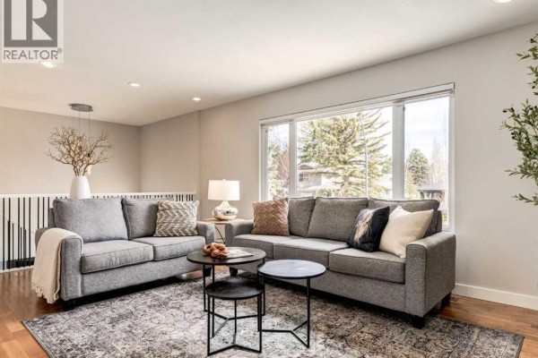 Living room with a fireplace, a dining area with a table and chairs in the background. - 176 Mapleburn Drive Se, Calgary