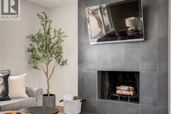 Living room with two sofas, a fireplace, and a large window overlooking the exterior. - 176 Mapleburn Drive Se, Calgary