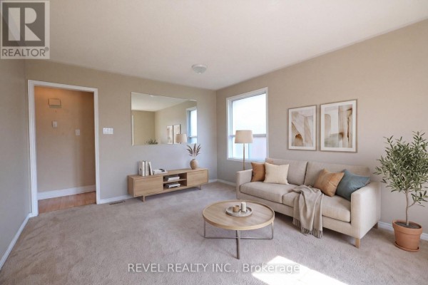 Living room with beige carpet, sofa, coffee table, and large mirror. - 176 Towerhill Road, Peterborough