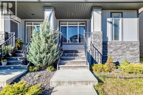 Close-up of duplex front entrance with stairs, stone accents, and landscaping. - 176 Willow Park, Cochrane