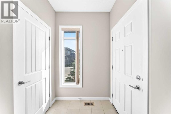 Interior entryway with beige tile floor, two white doors, and a tall window. - 176 Willow Park, Cochrane