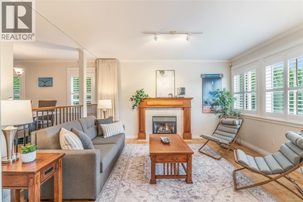 Living room with grey sofa, wooden coffee table, fireplace, and plantation shutters. - 1765 Admiral Tryon Blvd, French Creek
