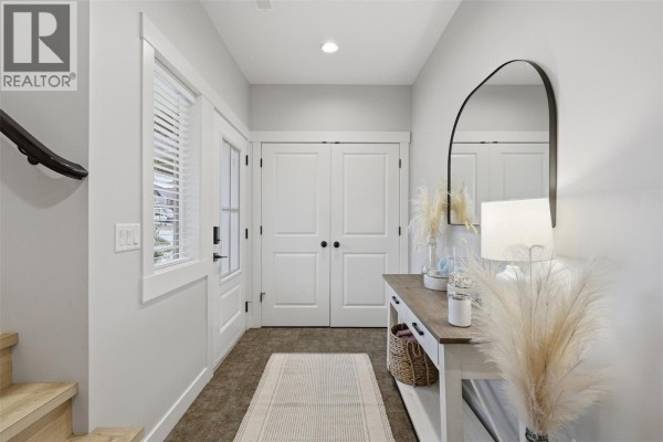 Interior view of a bright entryway with light grey walls, a white door, and double doors. - 1765 Foxtail Drive, Kamloops