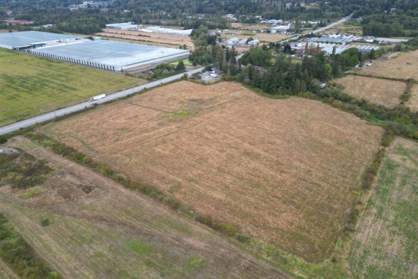 Expansive aerial view of farmland, a highway, and greenhouses in the distance. - 17690 12 Avenue, Surrey