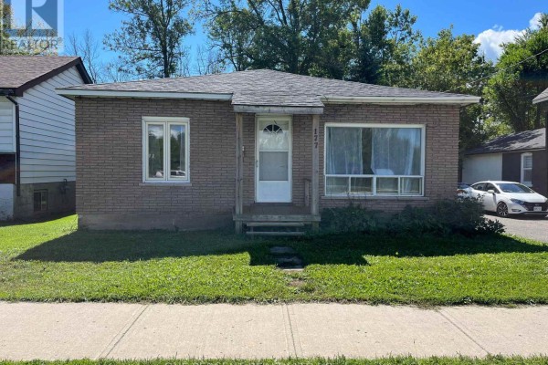 A light brown brick bungalow with a front porch and a car parked on the right. - 177 Atherley Road, Orillia