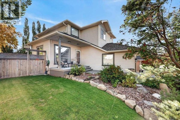 Rear exterior view of the house with a covered porch and landscaped backyard. - 177 Douglasview Rise Se, Calgary