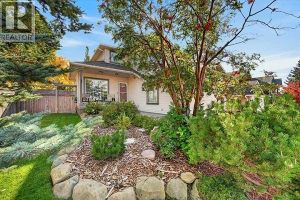 Side view of the house showing lush landscaping with mature trees and shrubs. - 177 Douglasview Rise Se, Calgary