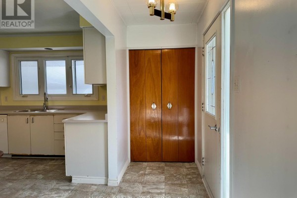 Entrance hallway with a double bi-fold wooden closet and a door with a decorative glass panel. - 177 Georgina Avenue, Temiskaming Shores