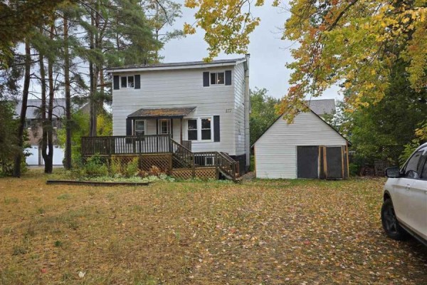 Exterior view of the house and detached garage, with trees and foliage in the foreground. - 177 River Rd, Sault Ste  Marie