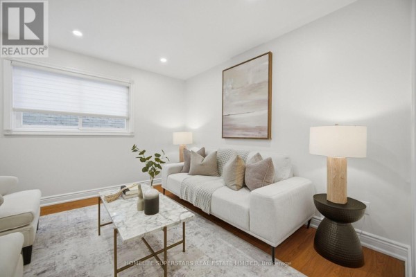 Living room with a white sofa, marble coffee table, floor-to-ceiling window with blinds, and hardwood floors. - 177 Surbray Grove, Mississauga