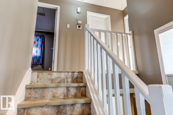 View looking down a staircase with beige tiled treads and white banisters. - 17703 90 St Nw, Edmonton