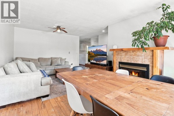 Living and dining area with a fireplace, sectional sofa, and large wooden dining table. - 1771 Harris Road, Squamish