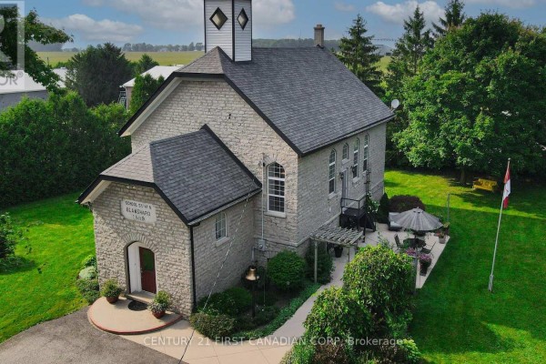 Aerial view of the stone building with a patio, lawn, and Canadian flag. - 1772 Perth Road 139 Road, St  Marys
