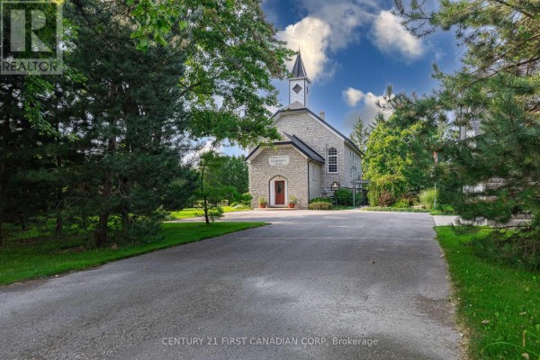 View of the stone building from a tree-lined driveway on a sunny day. - 1772 Perth Road 139 Road, St  Marys