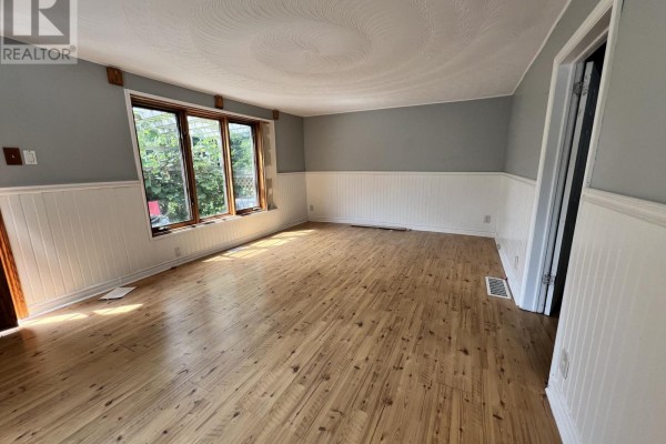 View of the living room with light wood floors, a large bay window, and grey walls. - 1773 20th Side Road, Innisfil