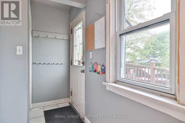 Empty basement room with beige tiled floor, grey paneled walls, and a small window. - 178 Angelene Street, Mississauga