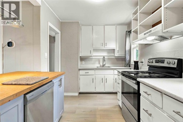 A white kitchen with light wood floors and butcher block island countertop. - 178 East Street North, Sarnia