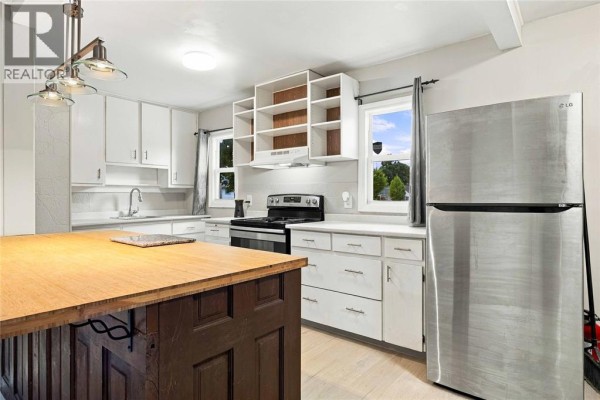 White kitchen cabinets, stainless steel refrigerator, and view out window. - 178 East Street North, Sarnia