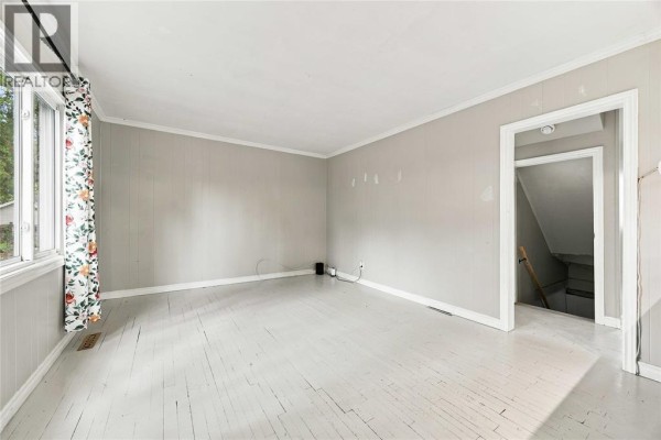 Living room with light grey paneled walls and painted white wood floors. - 178 East Street North, Sarnia